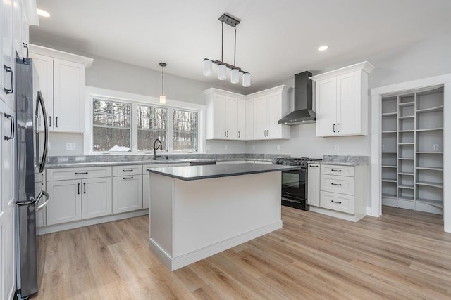 kitchen with stainless steel appliances, white cabinets, and wall chimney exhaust hood