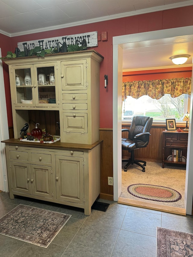 bar featuring crown molding, dark tile patterned floors, and cream cabinetry