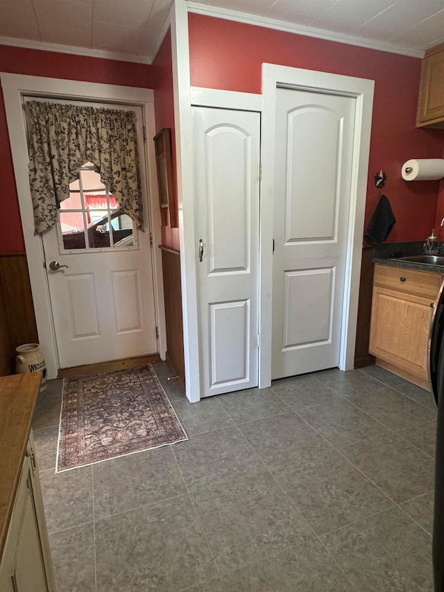 doorway to outside with sink, tile patterned flooring, and ornamental molding