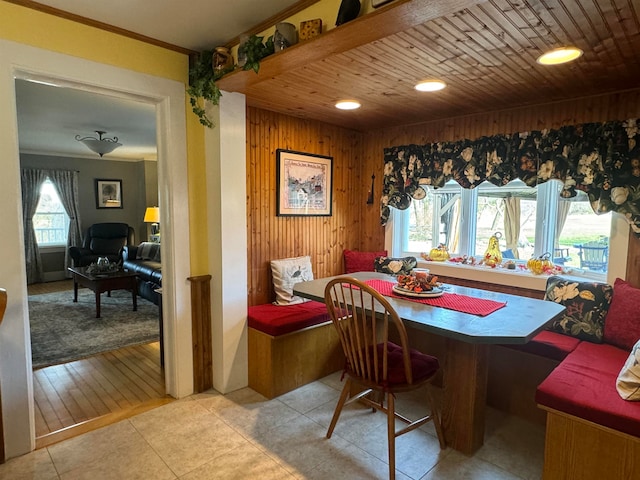 dining room with wood walls, light wood-type flooring, and crown molding