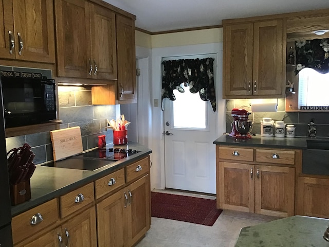 kitchen with light tile patterned flooring, backsplash, ornamental molding, and black appliances