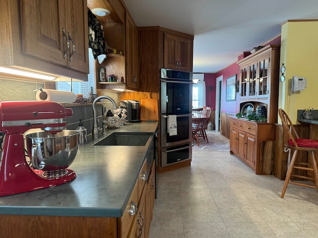 kitchen featuring sink, light tile patterned floors, and stainless steel double oven