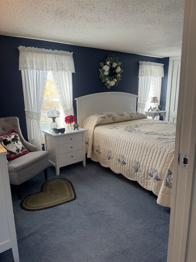 carpeted bedroom with a textured ceiling and multiple windows