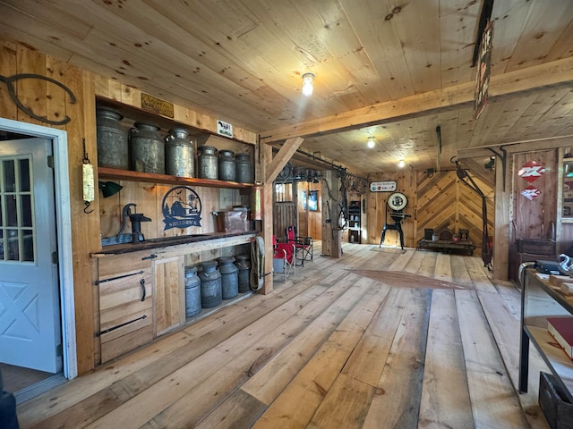 bar with beam ceiling, light hardwood / wood-style flooring, wooden walls, and wood ceiling