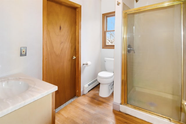 bathroom featuring hardwood / wood-style floors, vanity, a baseboard heating unit, toilet, and walk in shower