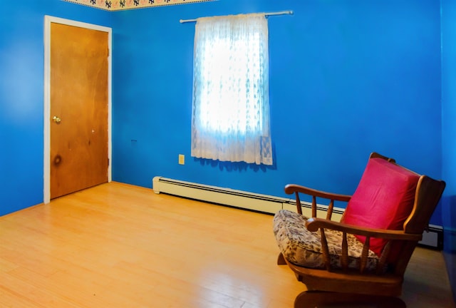 sitting room featuring hardwood / wood-style floors and a baseboard heating unit