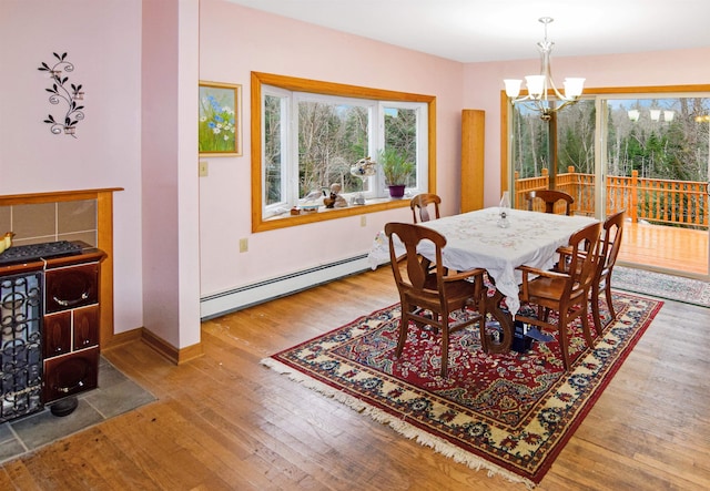 dining area featuring wood-type flooring, a baseboard radiator, and an inviting chandelier