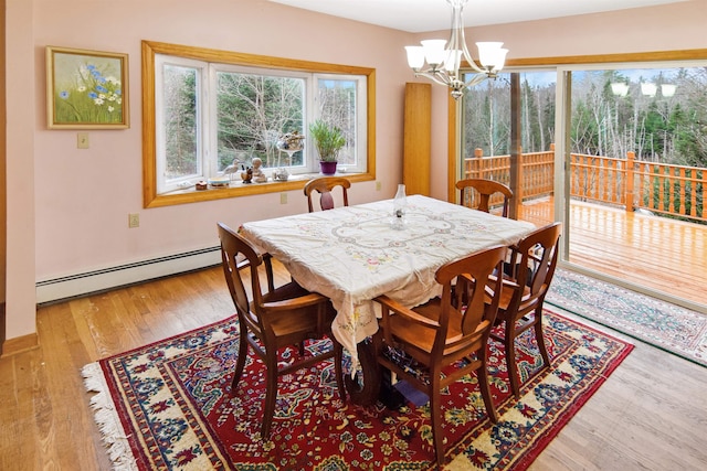 dining room featuring light hardwood / wood-style floors, baseboard heating, and an inviting chandelier