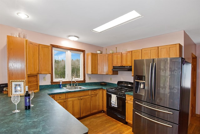 kitchen with sink, stainless steel fridge with ice dispenser, black range with gas cooktop, and light wood-type flooring