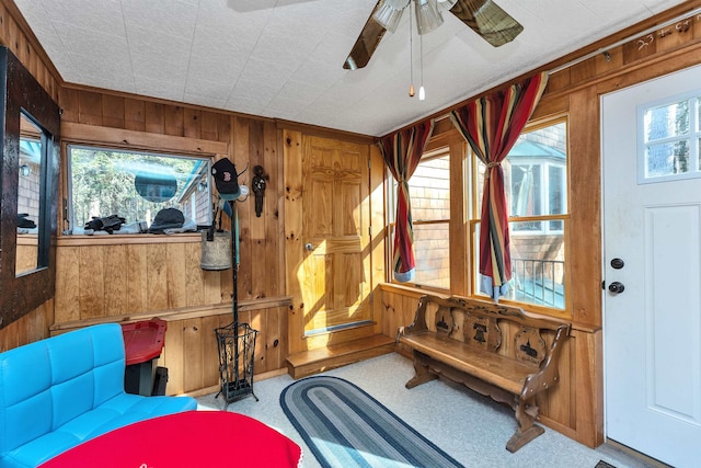 interior space featuring ceiling fan, light colored carpet, and wooden walls