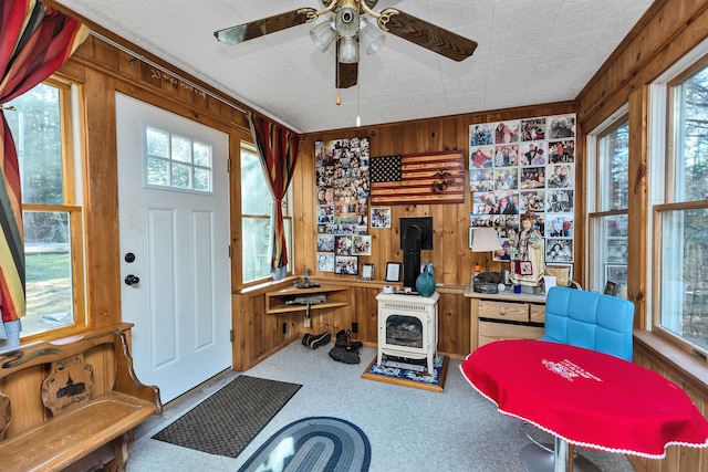 office space with a wood stove, wood walls, and ceiling fan