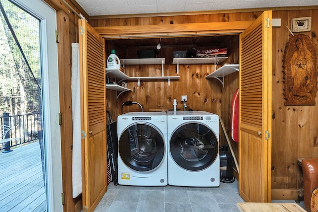 washroom with wooden walls and washing machine and clothes dryer