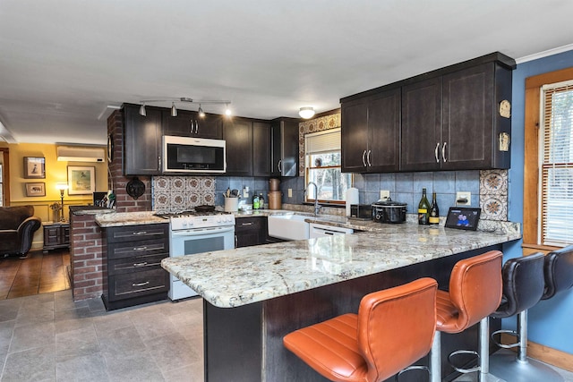 kitchen featuring kitchen peninsula, plenty of natural light, dark brown cabinets, and white stove