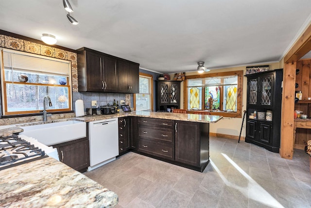 kitchen featuring dishwasher, light stone counters, backsplash, kitchen peninsula, and dark brown cabinets