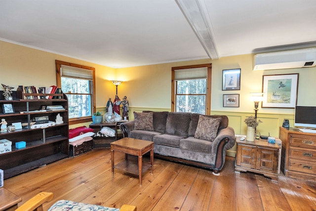 living room featuring hardwood / wood-style floors, a wall mounted AC, ornamental molding, and beam ceiling