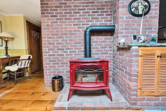 room details with hardwood / wood-style floors, a wood stove, and crown molding