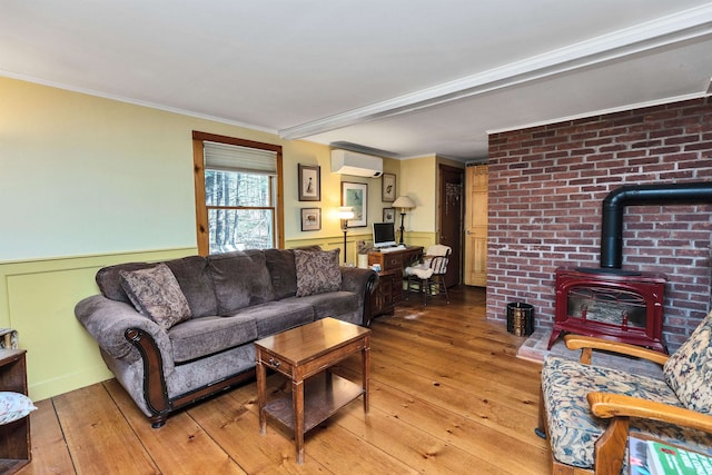 living room featuring an AC wall unit, a wood stove, crown molding, and hardwood / wood-style flooring