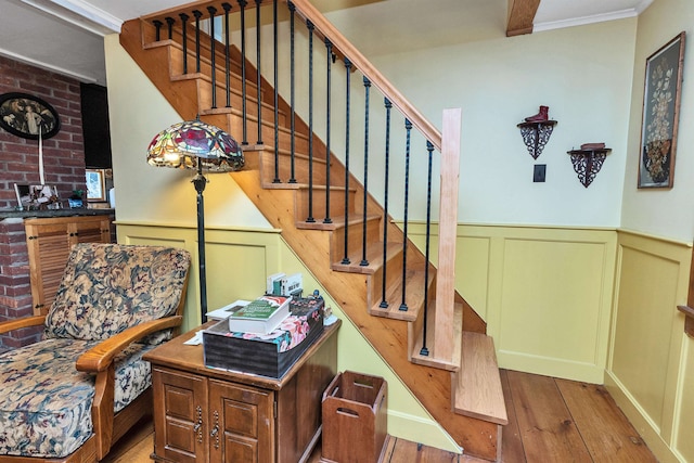 stairs with hardwood / wood-style flooring, crown molding, and brick wall