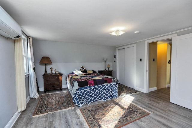 bedroom featuring a wall unit AC, a closet, and wood-type flooring