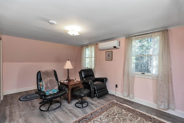 sitting room featuring a wall mounted air conditioner, wood-type flooring, and vaulted ceiling