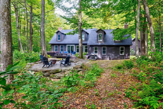 rear view of property with a patio and a fire pit