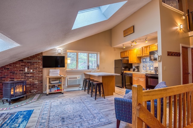 6S River Run Dr, Bartlett, NH 03812 - kitchen with black appliances, a skylight, lofted ceiling, a wood stove, and a kitchen breakfast bar