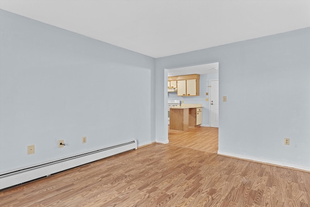 empty room featuring light wood-type flooring and a baseboard heating unit