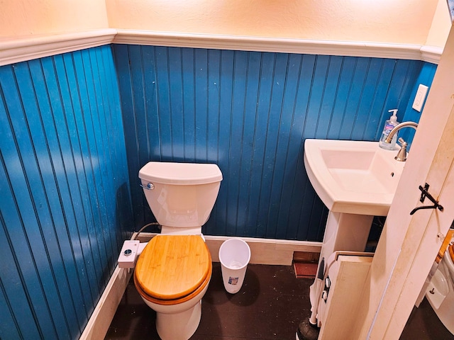 bathroom with wood walls and toilet