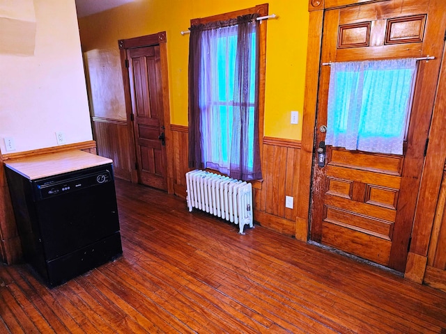 entrance foyer with radiator, wooden walls, and dark wood-type flooring