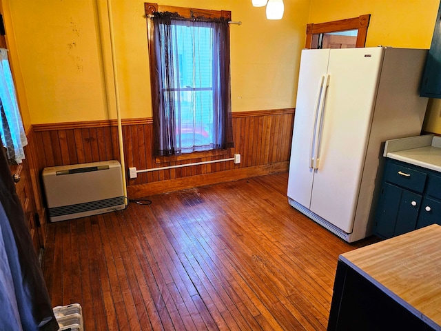 kitchen featuring wooden walls, white fridge, heating unit, and hardwood / wood-style flooring