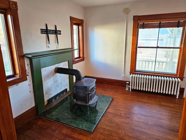 sitting room with radiator, dark hardwood / wood-style flooring, and a wood stove