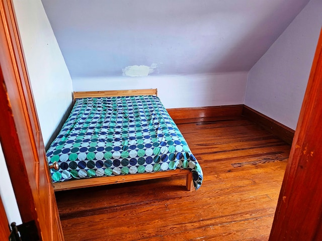 bedroom with wood-type flooring and vaulted ceiling