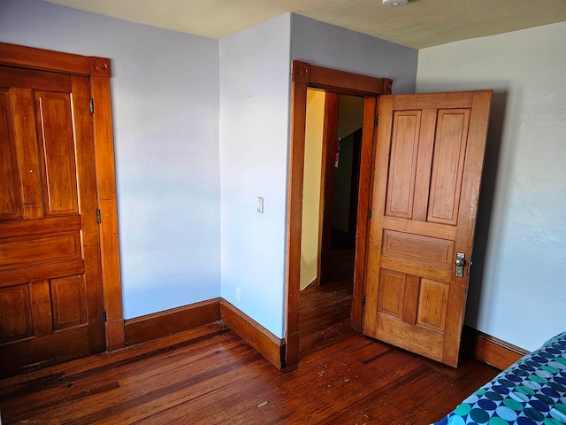 unfurnished bedroom with dark wood-type flooring