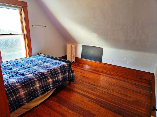 bedroom with hardwood / wood-style flooring, lofted ceiling, and radiator heating unit