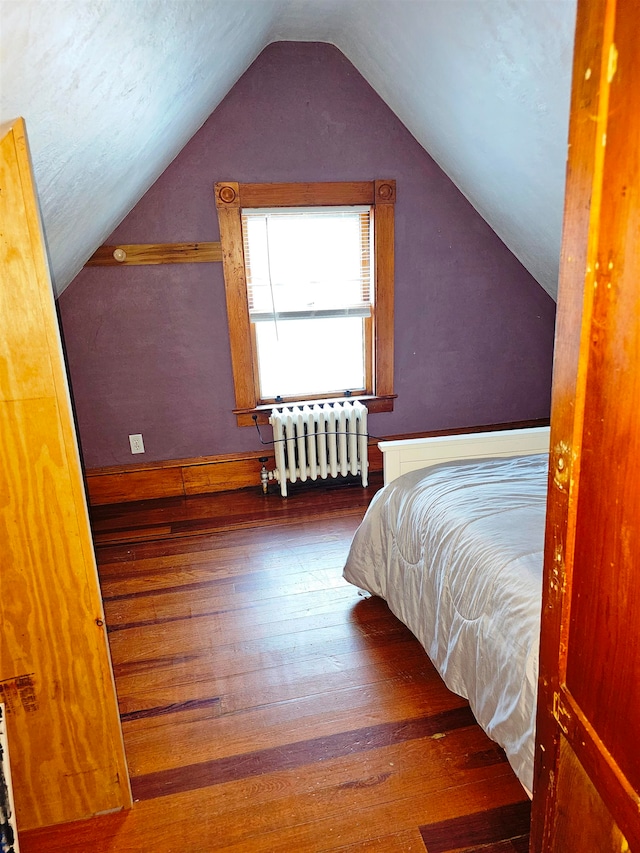 bedroom featuring radiator, dark wood-type flooring, and vaulted ceiling