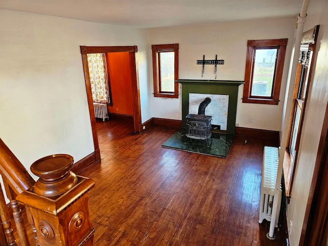 living room with dark hardwood / wood-style flooring, a wood stove, and radiator heating unit