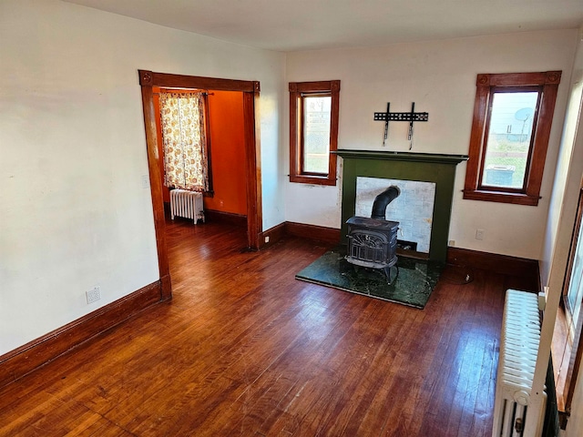 unfurnished living room featuring a wood stove, dark hardwood / wood-style floors, and radiator