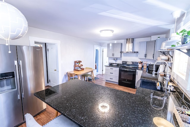 kitchen with electric range, sink, wall chimney exhaust hood, stainless steel fridge with ice dispenser, and hardwood / wood-style flooring