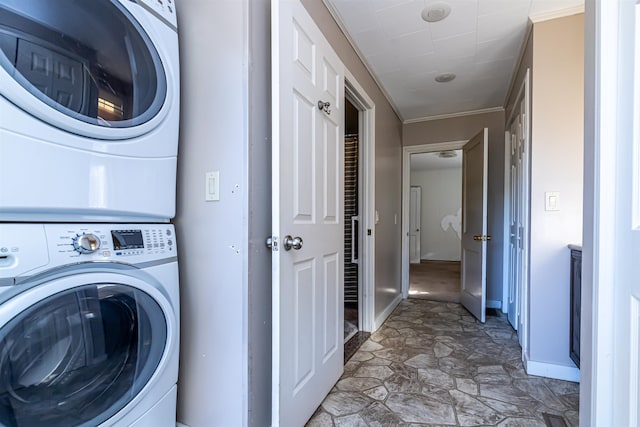 clothes washing area featuring crown molding and stacked washer and clothes dryer