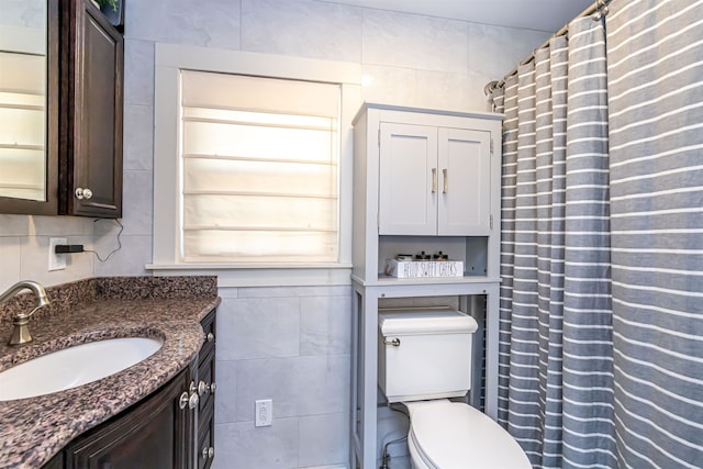 bathroom featuring vanity, toilet, and tile walls