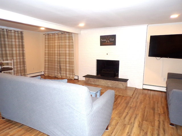 living room featuring hardwood / wood-style flooring, a large fireplace, crown molding, and baseboard heating