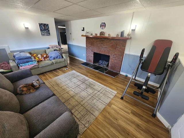 living room featuring a paneled ceiling, hardwood / wood-style floors, and a fireplace