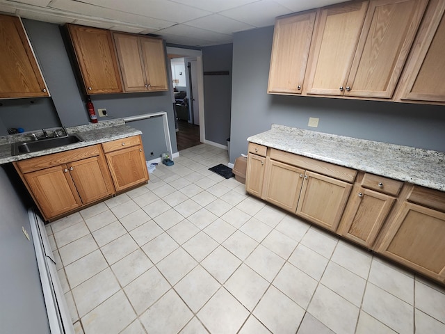 kitchen with sink, a drop ceiling, and light stone counters