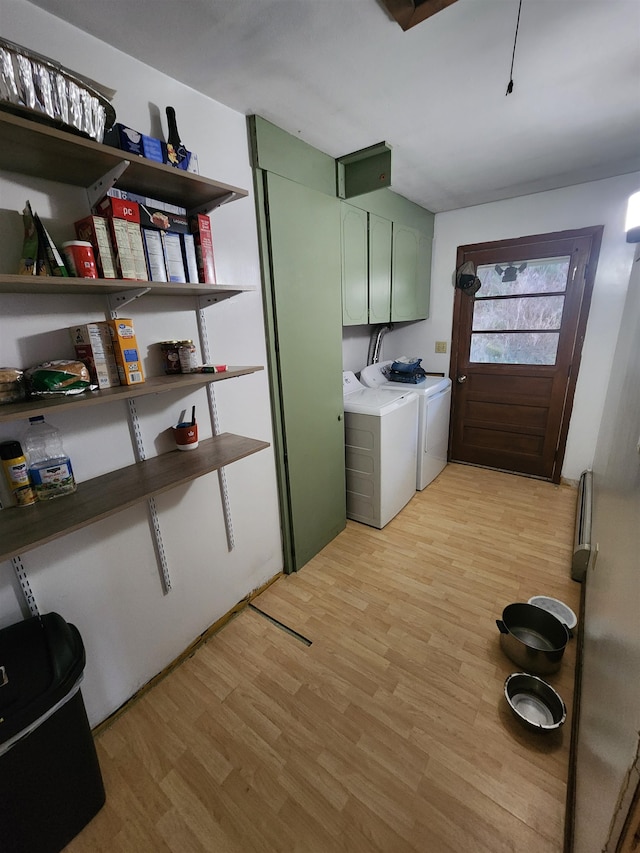 washroom featuring independent washer and dryer, cabinets, and light hardwood / wood-style flooring