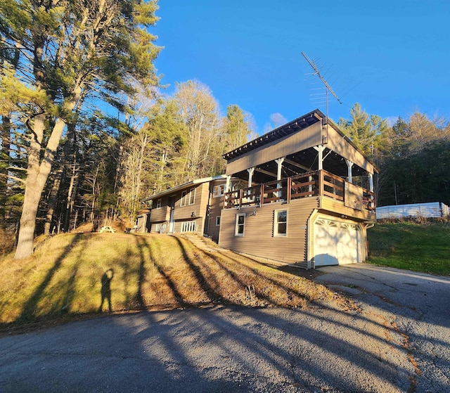 view of property exterior featuring a garage, a deck, and a lawn