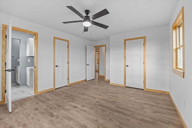 unfurnished bedroom featuring light wood-type flooring, ensuite bathroom, and ceiling fan