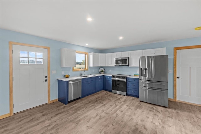 kitchen featuring stainless steel appliances, blue cabinets, sink, light hardwood / wood-style floors, and white cabinetry