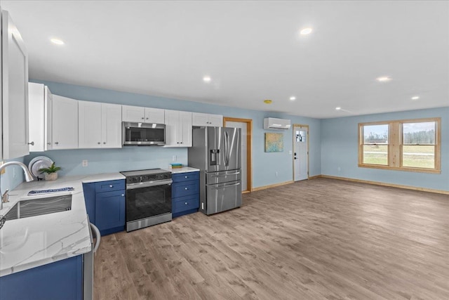 kitchen featuring sink, light hardwood / wood-style floors, white cabinetry, stainless steel appliances, and a wall unit AC