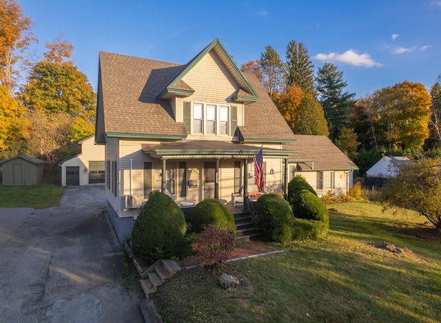 view of front of house with a porch, a garage, an outdoor structure, and a front yard