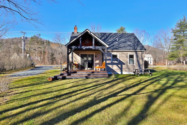 rear view of property featuring a wooden deck and a lawn